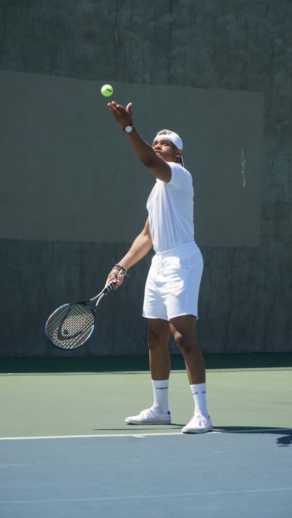 A Man in White Shirt and White Shorts Holding a Tennis Racket